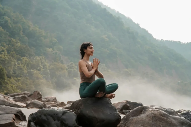 Entrada-Meditacion-ciencia mujer sentada en pode de meditacion con manos juntas en el pecho sentada en una roca